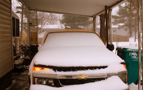 Voiture recouverte de neige sous un CARPORT